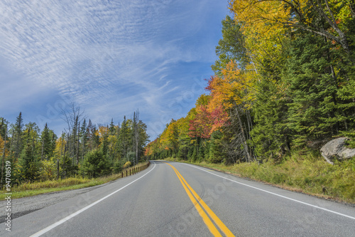 Fall colors light up along a country road on a bright sunny day. © spectrumx86