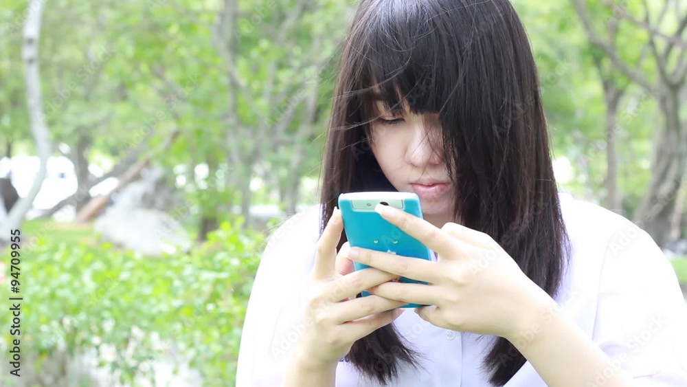 Portrait of thai student teen beautiful girl using her smart phone sitting in park. Portrait of thai student teen beautiful girl using her smart phone sitting in park.