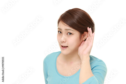 young woman with hand behind ear listening closely