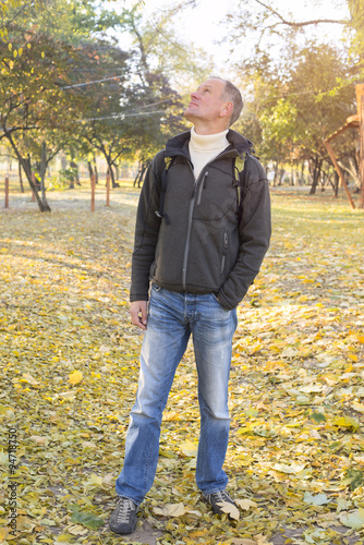 Attractive man with backpack relaxing in a autumn park, stands a © sanechka