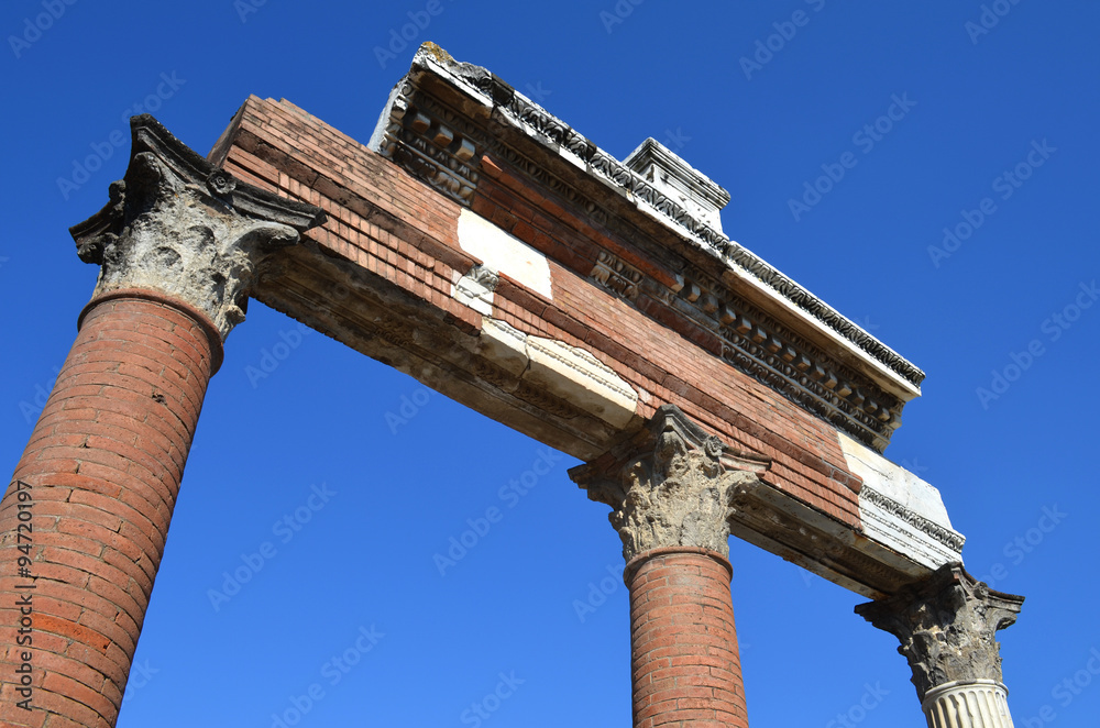 Columns and entablature fragment of an ancient temple in Pompeii against the sky

