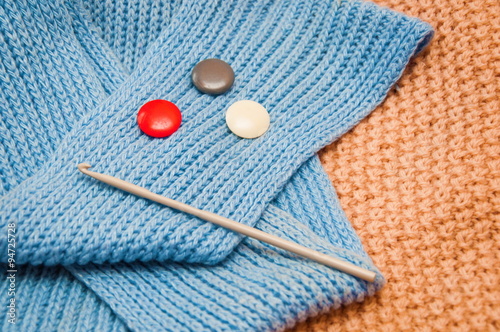 Knitting needle and colorful buttons on the crochet fabric