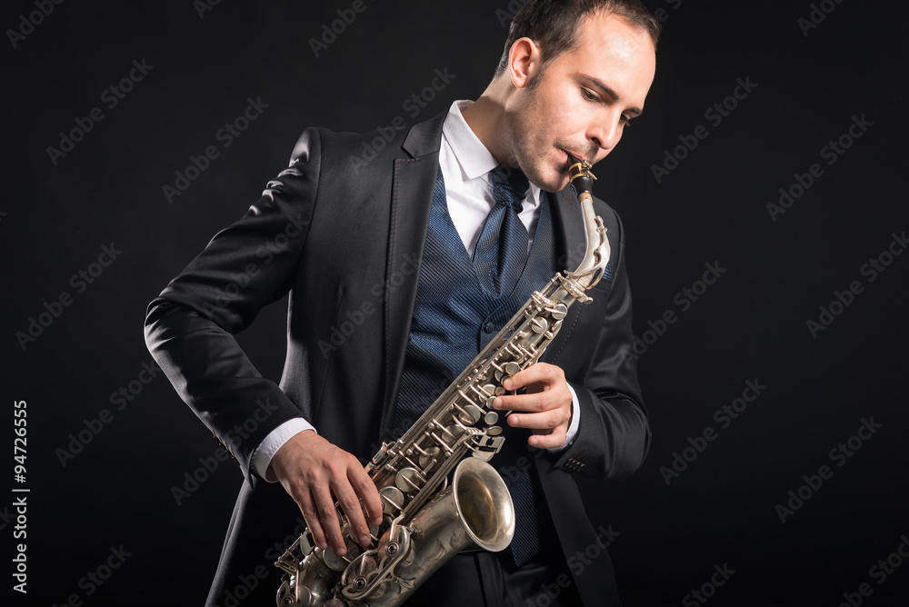 Naklejka premium Saxophone player man isolated against black background. Close up