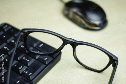 closeup of glasses , keyboard and mouse on table