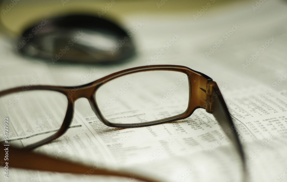 Office life,closeup of a glasses on a newspaper Office life,closeup of a glasses on a newspaper