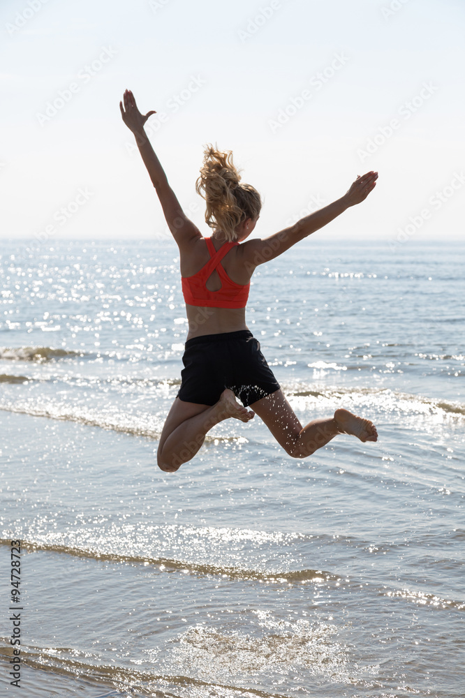 woman cheering and jumping on a beach in sunset woman cheering and jumping on a beach in sunset