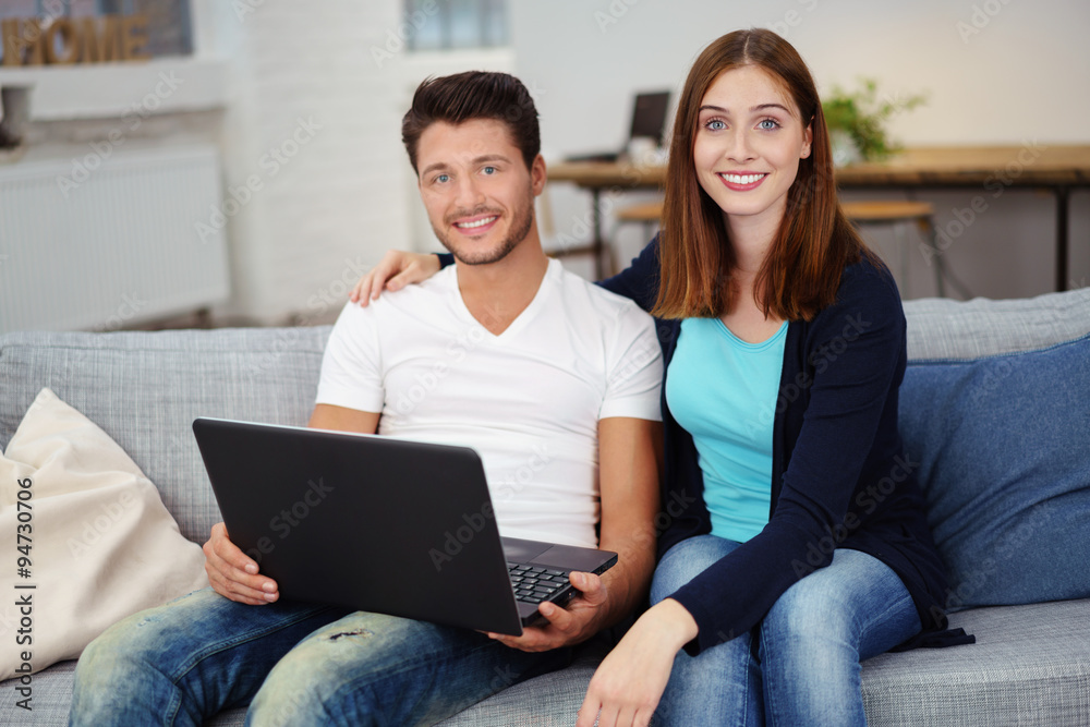 junges paar mit laptop auf dem sofa in einer modernen loftwohnung