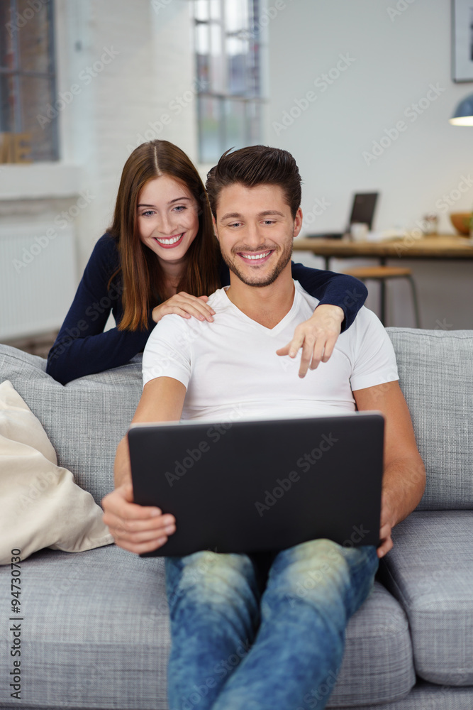 ein modernes paar in seiner wohnung schaut auf den laptop ein modernes paar in seiner wohnung schaut auf den laptop