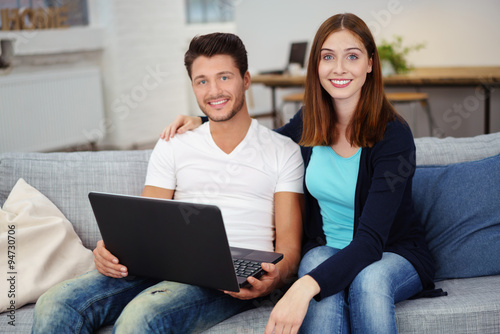 junges paar mit laptop auf dem sofa in einer modernen loftwohnung