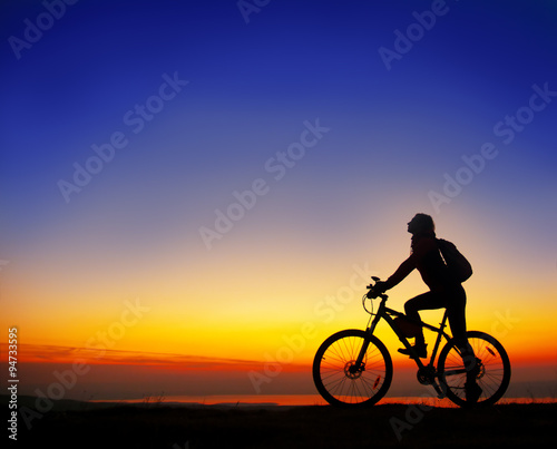 Girl with a bicycle watching the sunset