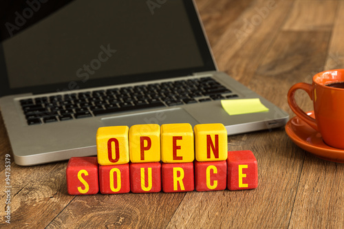 Canvas Print Open Source written on a wooden cube in front of a laptop