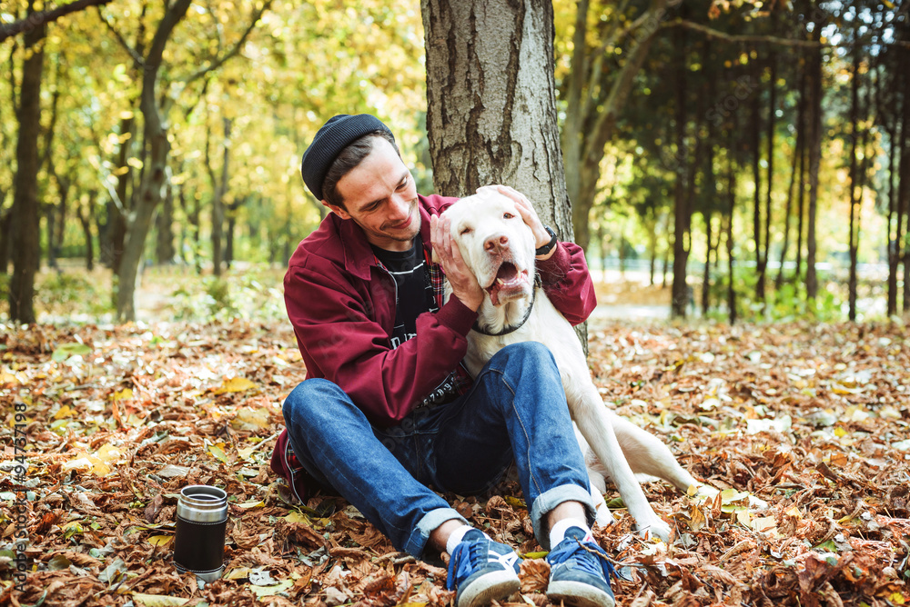 man drinking coffee in park and playing with labrador dog man drinking coffee in park and playing with labrador dog