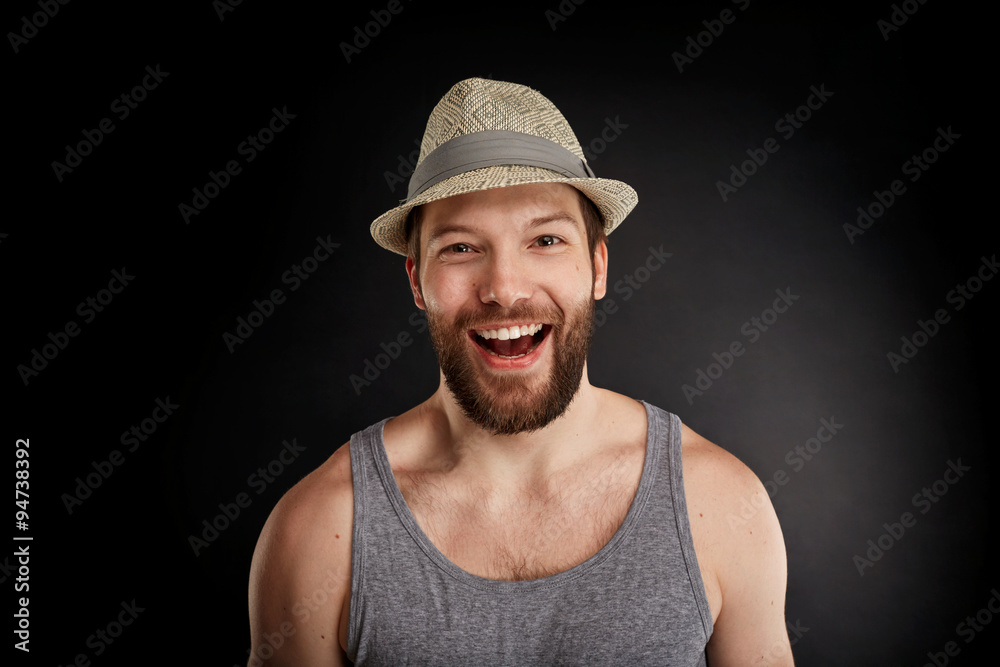 Happy smiling handsome hipster man posing. Bearded man in t-shirt looking at the camera isolated on black background.