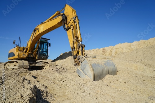 Gelber Bagger in einer Sandkuhle am baggern photo