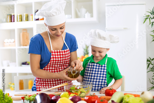 Mother and child putting olive oil to vegetables lettuce