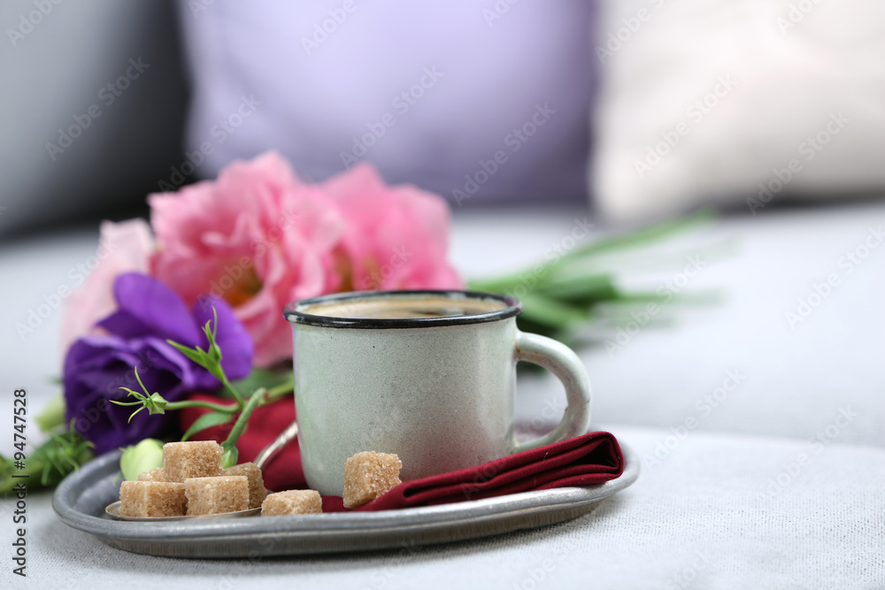 Cup of coffee with flowers on tray on sofa in room Cup of coffee with flowers on tray on sofa in room
