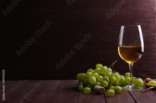 Glass of wine with grape on wooden background