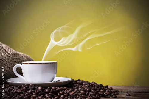 Cup with hot coffee against grunge background