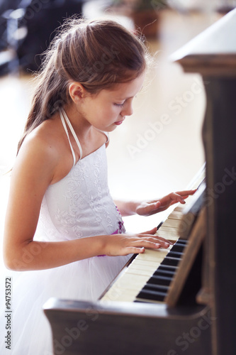 Attractive little princess girl plays piano