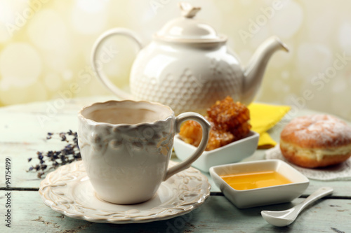 Honeycomb  bowl with honey  teapot on color wooden background