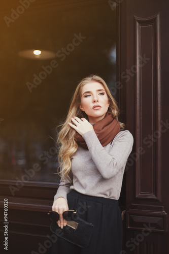 Street fashion concept: portrait of young beautiful lady standing at the window