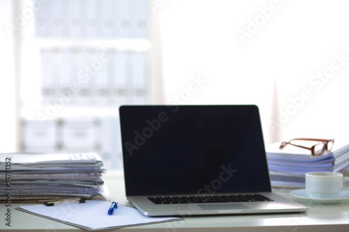 Laptop with stack of folders on table on white background