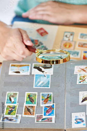 Postage stamp with birds under magnifier on album