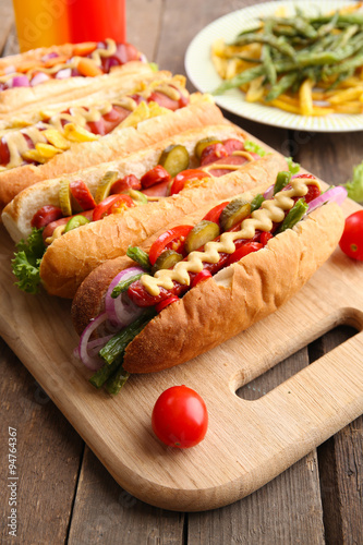 Fresh hot dogs on cutting board and food on plate closeup