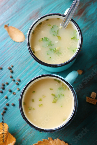 Two mugs of soup on blue wooden background