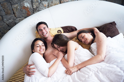 handsome man in bed with three beautiful woman photo