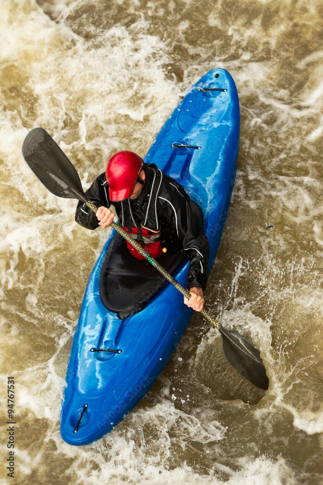 A man in an extreme sports kayak, navigating through rough waters on a plastic rafting adventure. A man in an extreme sports kayak, navigating through rough waters on a plastic rafting adventure.