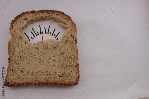 Wholesome slice of bread as weighing scale. whole bread look like a weighing for weight control, concept. metaphor photography, allegory . fork and knife near weighing bread for healthy lifestyle. photo
