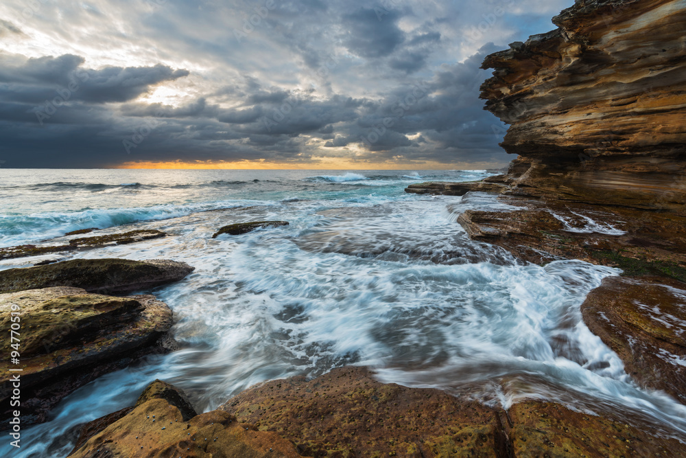 Fototapeta premium Seascape sunrise with unrest sea and grim sky and cliffs