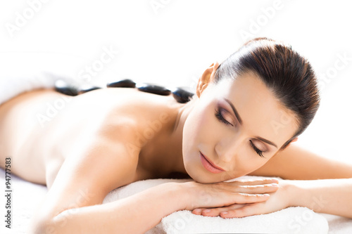 Beautiful woman having hot stones on her back in spa salon.