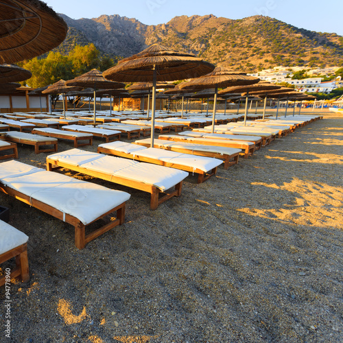 Rows of empty white sunbeds on beach in the afternoon