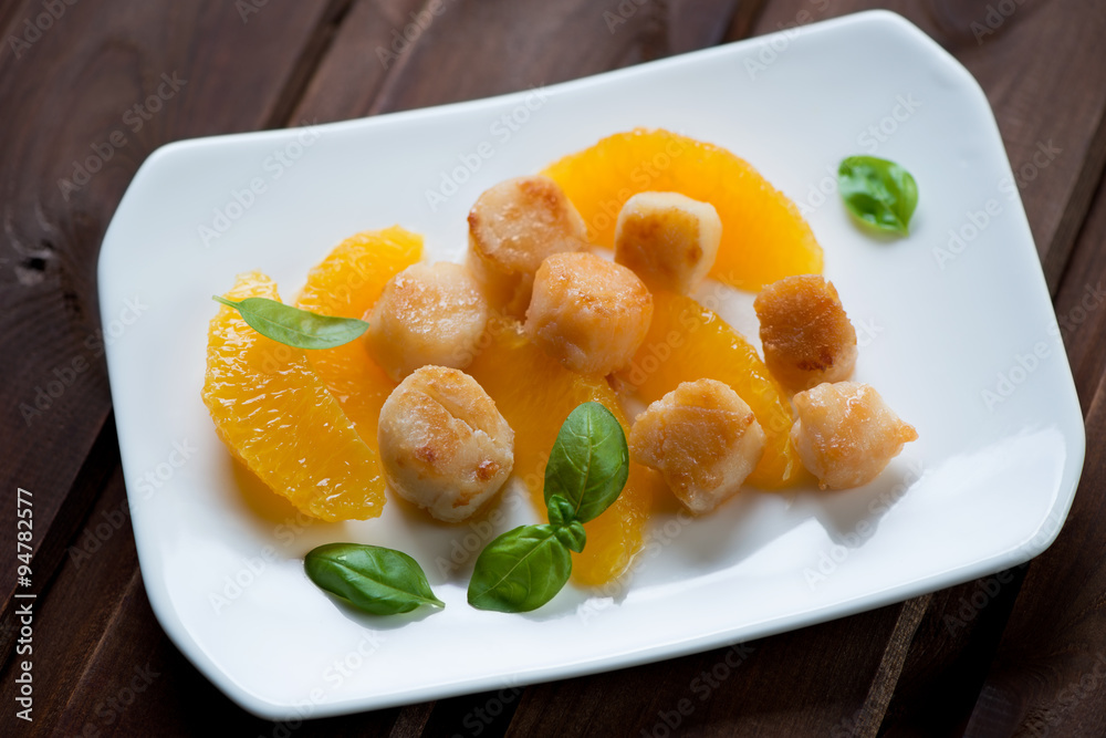 Roasted scallops with orange fillet and green basil, studio shot Roasted scallops with orange fillet and green basil, studio shot