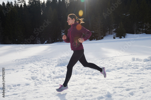 yougn woman jogging outdoor on snow in forest photo