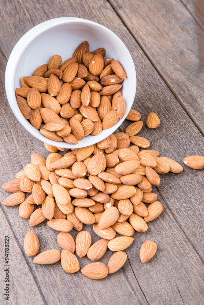 Almonds in white bowl on wooden Almonds in white bowl on wooden