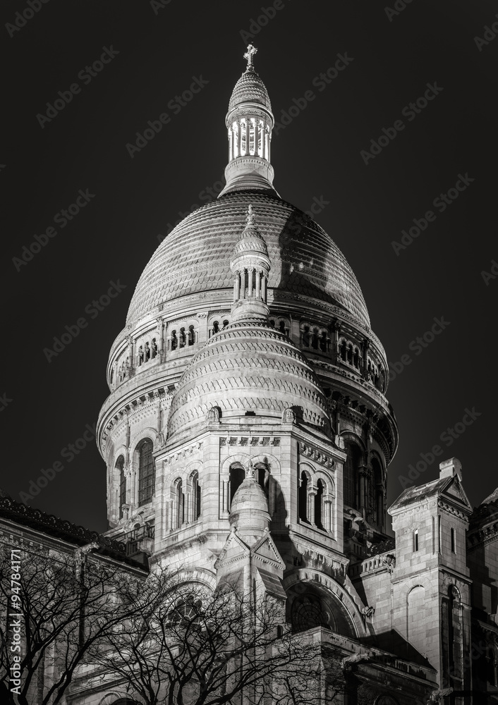 Black & White view of the domes of Sacré Coeur Basilica (Sacred Heart) in Montmartre. The Romano-Byzantine architectural style basilica is illuminated at night. (18th arrondissement), Paris, France.