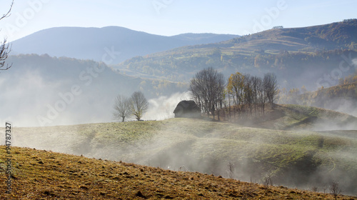 Small cottage in the mountains in the morning fog photo