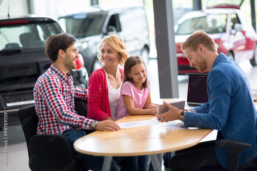 Fototapeta premium Car salesperson demonstrating new car to family