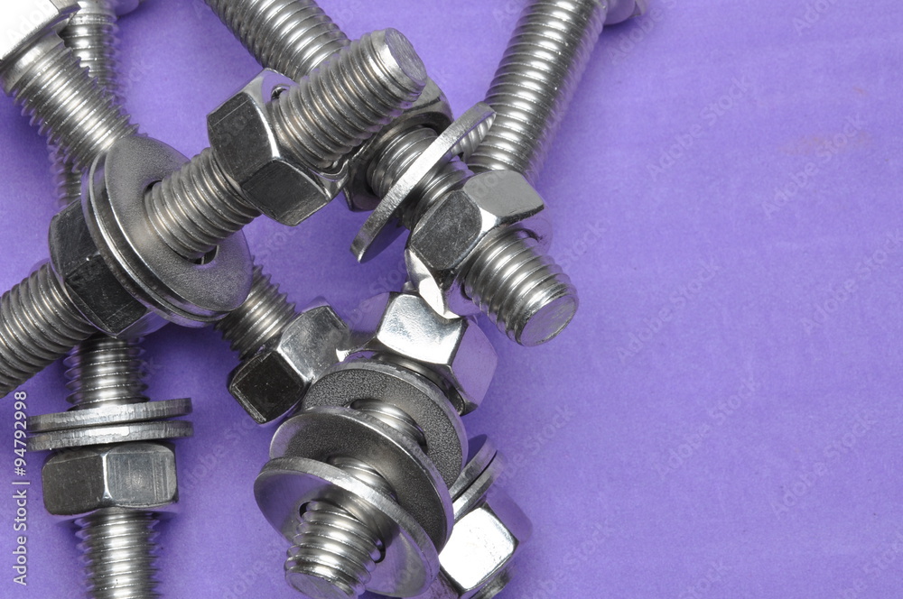 Bolts and nuts on violet background with place for text Bolts and nuts on violet background with place for text