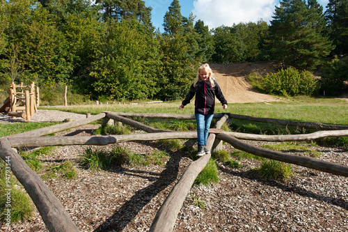Young girl play in a creative playground in the middle of nature