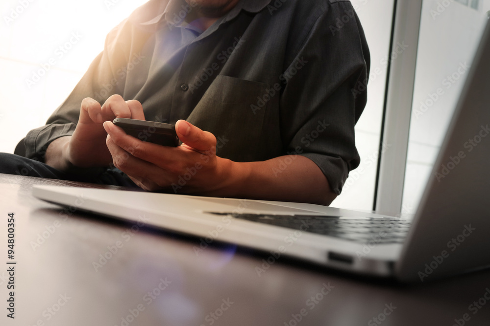 designer hand working and smart phone and laptop on wooden desk