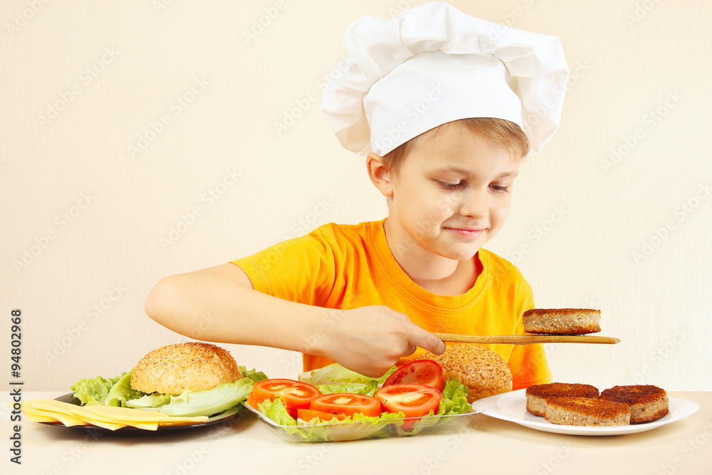 Little funny chef puts meat on the hamburger Little funny chef puts meat on the hamburger