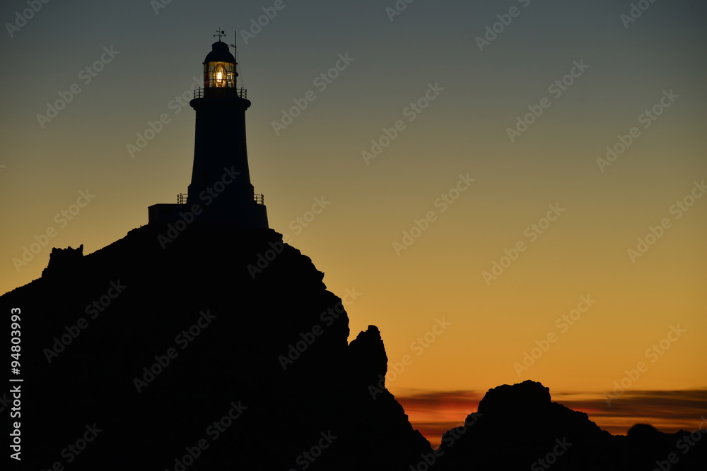La Corbiere lighthouse, Jersey, U.K.   Telephoto image of a coastal structure at sunset.