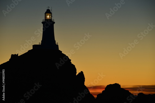 La Corbiere lighthouse, Jersey, U.K. Telephoto image of a coastal structure at sunset.