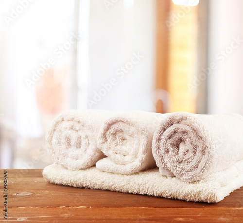 Rolled bath towels on wooden table in bathroom