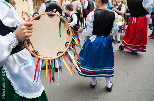 Girl with a typical regional dress playing a colored tambourine during a folkloristic show in Sicily