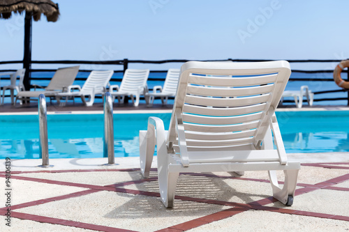 Lounge sunbeds near swimming pool © photopixel